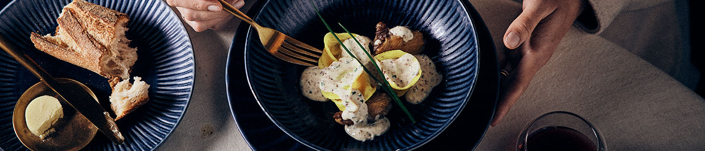 Duck and Spinach & Ricotta Tortellini in a bowl, with bread and butter, and a glass of wine on table