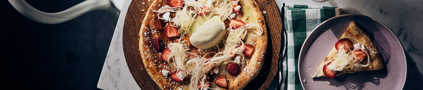 Dessert Pizza with strawberries, white chocolate and fairy floss on a table.