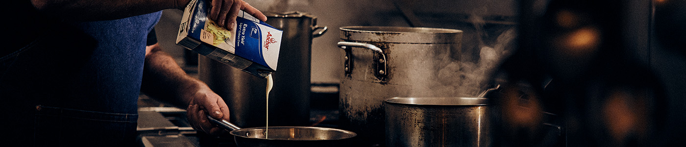 Cream pouring from the carton into a pan in commercial kitchen